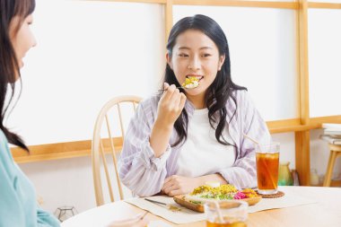 İki genç Japon kadın restoranda yemek yiyor.