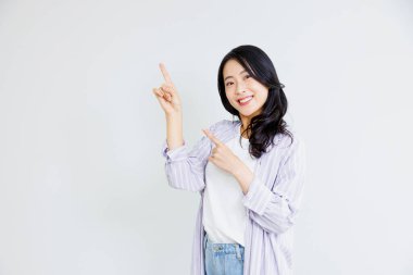 Gülümseyen Asyalı genç kadın boş alanı işaret ediyor.