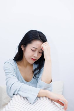 Asyalı kadın evde baş ağrısı çekiyor. 