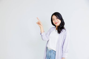 Gülümseyen Asyalı genç kadın boş alanı işaret ediyor.