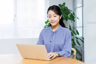 Dizüstü bilgisayarı olan genç Asyalı kadın.