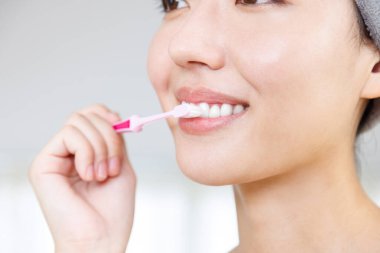 Banyoda diş fırçası olan genç Asyalı kadın. 