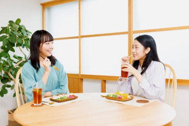 İki genç Japon kadın restoranda yemek yiyor.