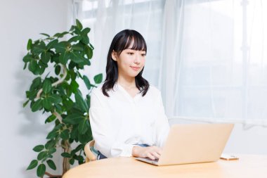 Ofiste bilgisayar kullanan genç Asyalı kadın. 