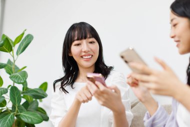 Akıllı telefonları olan Asyalı arkadaşlar evde sohbet ediyorlar.