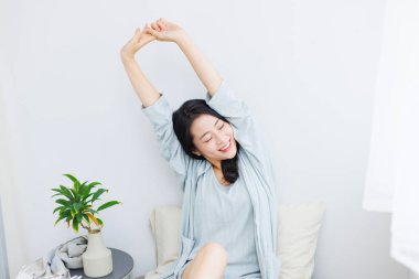 Genç Asyalı kadın evdeki kanepede dinleniyor. 