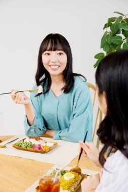 İki genç Japon kadın restoranda yemek yiyor.