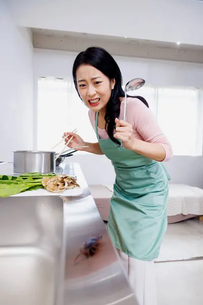 Scared Japanese woman looking at bug on sink in the kitchen