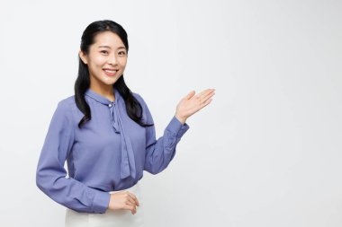 Genç Asyalı iş kadını gri arkaplanda kopya alanı gösteriyor