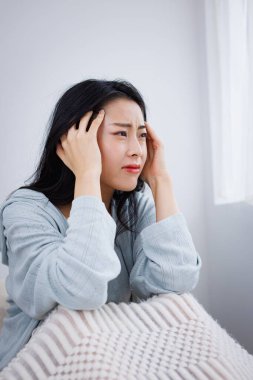 Genç Asyalı kadın baş ağrısı çekiyor ve migren ağrısı çekiyor.