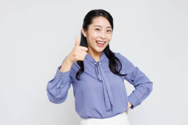 Tebessüm eden Asyalı kadın beyaz arka planda parmak gösteriyor.