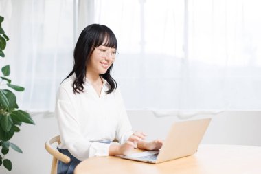 Genç Asyalı kadın ofiste dizüstü bilgisayar kullanıyor. 