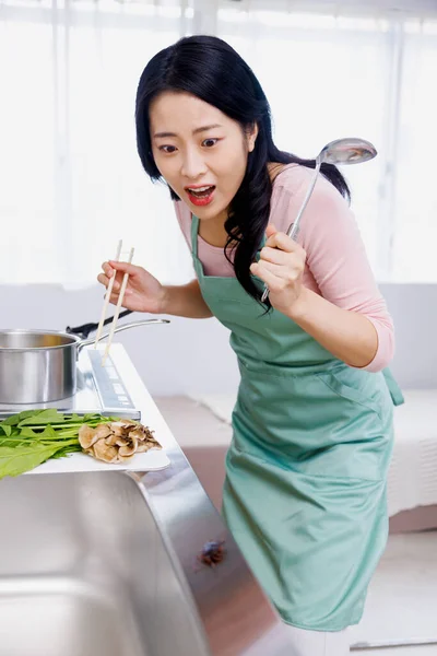 Scared Japanese woman looking at bug on sink in the kitchen