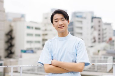 Kollarını kavuşturmuş Asyalı erkek hemşire.