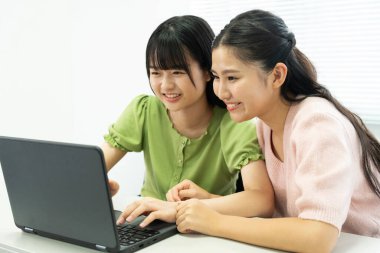 Laptop kullanan iki Asyalı öğrencinin portresi