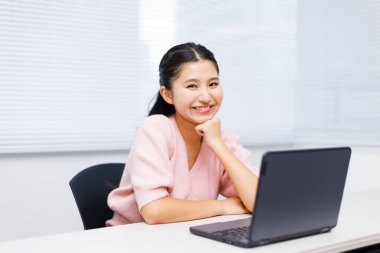 Sınıfta dizüstü bilgisayar kullanan Asyalı genç kız öğrenci.