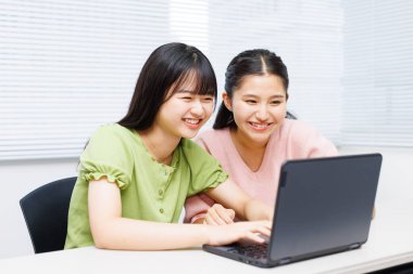 Sınıfta dizüstü bilgisayar kullanan iki kız öğrenci.