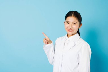 Laboratuvar önlüklü mutlu öğrencinin portresi mavi arka planda kameraya gülümsüyor.