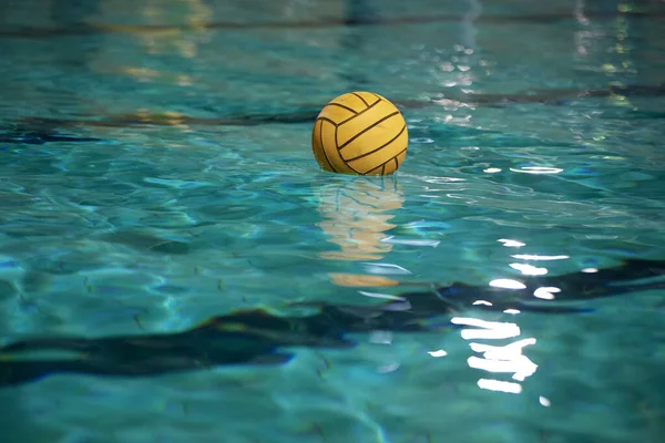 Water polo. Yellow water polo ball in a swimming pool on blue water background
