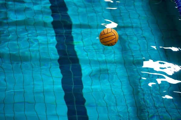 Water polo. Yellow water polo ball in a swimming pool on blue water background