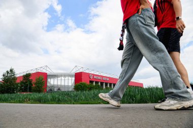Mainz, Almanya - 17 Mayıs 2025: Futbol taraftarları Mewa ArENA 'ya doğru yürüyorlar. FSV Mainz 05, renkli çiçek tarlalarının arkasında görüldü. Bundesliga eşleşmesi öncesinde manzaralı atmosfer oluşturuluyor.