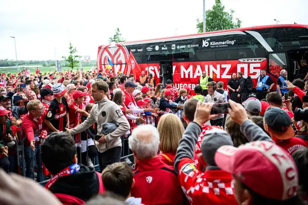 MAINZ, ALMANY - 17 MAYIS, 2025: 1 destekçileri. FSV Mainz 05, ekip otobüsüne hoş geldiniz. Kırmızı giyinmiş hayranlar, ellerinde eşarplar ve telefonlar, maç öncesi atmosfer. Maç Mewa Arena 'da Bayer 04' e karşı.