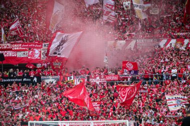 MAINZ, GERMANY - 17 Mayıs 2025: MeWA ARENA 'daki Bundesliga maçı sırasında FSV Mainz 05 bayrakları ve kırmızı dumanı yoğun bir fan atmosferi yarattı.