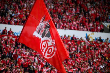 MAINZ, GERMANY - 17 Mayıs 2025: MeWA ARENA 'da oynanan Bundesliga maçı sırasında hayranlar arasında FSV Mainz 05 logosu ve katedral silueti dalgalı büyük bir kırmızı bayrak.