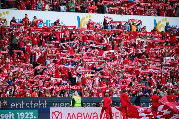 MAINZ, ALMANY - 17 MAYIS, 2025: 1 büyük kalabalık. FSV Mainz 05 taraftarları, MEWA ARENA 'da oynanan Bundesliga maçında kırmızı eşarpları aynı anda havada tutuyor. Taraftarların birliği ve coşkusu.
