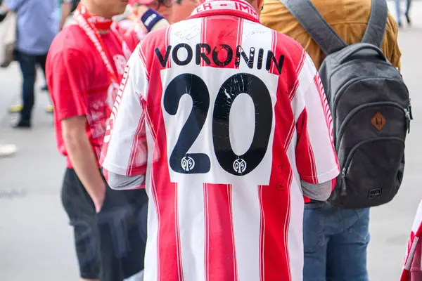 MAINZ, GERMANY - 17 Mayıs 2025: FSV Mainz 05 hayranı Voronin 20 ile retro forma giyer ve MEWA ARENA 'daki Bundesliga maçından önce imza verir. Futbol taraftarları etrafta görülüyor.