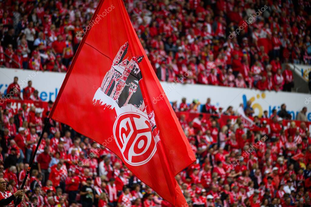 MAINZ, GERMANY - 17 MAY, 2025: A large red flag with the FSV Mainz 05 logo and cathedral silhouette waves among fans during a Bundesliga match at MEWA ARENA.