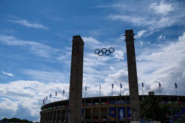 BERLİN, GERMANY - 14 HAZİRAN, 2024: Olimpiyat halkaları Berlin 'deki Olympiastadion kuleleri arasında asılı, UEFA EURO 2024 için dekore edilmiştir. Dramatik bahar gökyüzü altında tarihi stadyum.