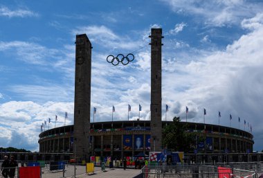 BERLİN, GERMANY - 14 HAZİRAN, 2024: Olimpiyat halkaları Berlin 'deki Olympiastadion kuleleri arasında asılı, UEFA EURO 2024 için dekore edilmiştir. Dramatik bahar gökyüzü altında tarihi stadyum.