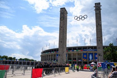 BERLİN, GERMANY - 14 HAZİRAN, 2024: Olimpiyat halkaları Berlin 'deki Olympiastadion kuleleri arasında asılı, UEFA EURO 2024 için dekore edilmiştir. Dramatik bahar gökyüzü altında tarihi stadyum.