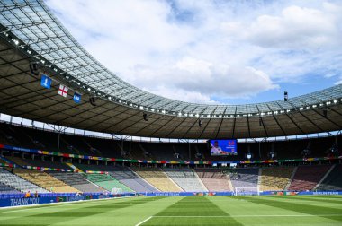 BERLİN, Almanya - 14 HAZİRAN 2024: UEFA EURO 2024 karşılaşması öncesinde Olympiastadion Berlin 'in iç görünümü. Boş tribünler, parlak gökyüzü ve stadyum ışıkları altında bayraklarla süslenmiş..