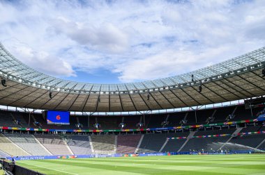 BERLİN, Almanya - 14 HAZİRAN 2024: UEFA EURO 2024 karşılaşması öncesinde Olympiastadion Berlin 'in iç görünümü. Boş tribünler, parlak gökyüzü ve stadyum ışıkları altında bayraklarla süslenmiş..