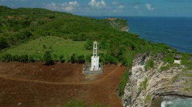 Uçurumun kıyısında duran beyaz bir deniz fenerinin etrafındaki insansız hava aracından dairesel bir uçuş. Okyanustaki uçurum, okyanus manzarası sunuyor. Yüksek kalite 4k görüntü.