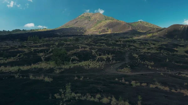 一个年轻的女人穿过火山附近的山区 火山上有黑色熔岩的山路自由 健康生活方式的概念 — 图库照片