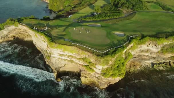 カントリークラブでゴルフをする人たちのドローン映像が海の崖にぶら下がった 海岸のグリーンゴルフコース 人々はゴルフをする 高品質の4K映像 — ストック動画