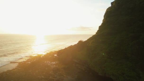 在落日的橙色灯光下 无人驾驶飞机在绿色岩石上飞来飞去 在阳光的映衬下 镜框中的阳光 温暖的阴影 在阳光下的海面上悬崖 — 图库视频影像