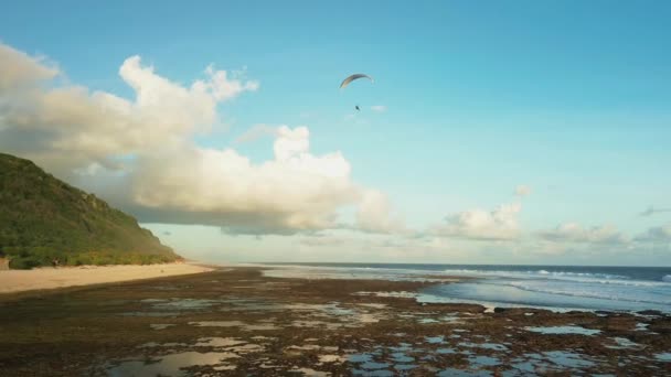 在海滨金色的时刻 一艘滑翔机在日落时飞翔 背景是绿色的小山 背景是在橙色的阳光下 一个人在芦笋上的轮廓 — 图库视频影像