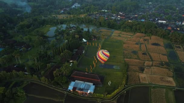 虹色の風船の上から下に撮影 熱気球は熱帯の島の田んぼに着陸する バリ島のインドネシアでのアトラクションやアウトドア活動 — ストック動画