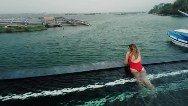 Widok Tyłu Młodej Kobiety Czerwonym Stroju Kąpielowym Patrzącej Jezioro Basenu — Wideo stockowe