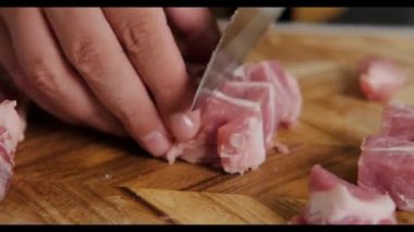 Bir adamın elinin çiğ eti parçalara ayırdığı yakın plan bir fotoğraf. Evde, mutfakta çiğ et pişirmek. Tahta kesme tahtasıyla et keser..