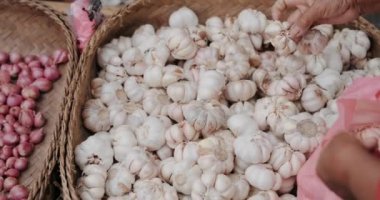 Yaşlı bir kadın marketten sarımsak seçiyor ve plastik bir torbaya koyuyor. Geleneksel organik sebze ve meyve pazarı. Marketten sebze ve sarımsak almak..