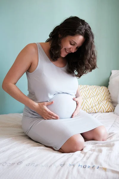 Foto Vertical Una Mujer Embarazada Sentada Cama Abrazando Gran Vientre — Foto de Stock