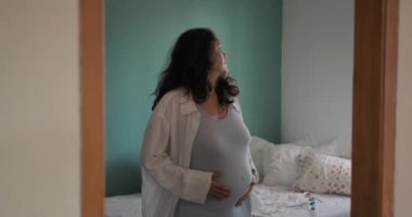 Güzel hamile bir kadın dans eder ve nazikçe karnını okşar. Rahatlayan ve müzikten zevk alan hamile bir kadının koca göbeği. Komik dans, hamile bir kadın..