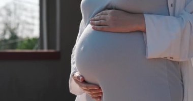 Hamile bir kadının karnının yandan görünüşü, içindeki bebek itiyor. Sağlıklı hamilelik ve jinekoloji. Hamileliği ve doğumu izliyor. Bir kadın hamile karnını okşar..