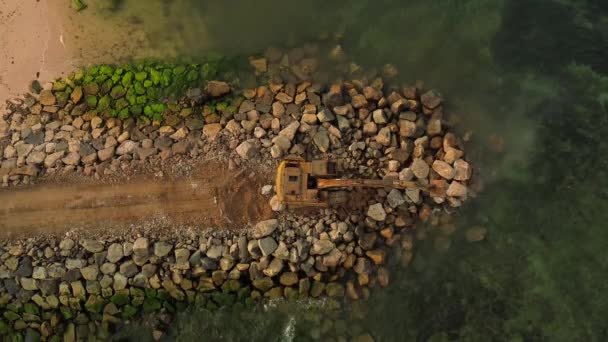 在海滩上靠近海洋的建筑工地工作的爬虫挖掘机的空中视图 在工地挖掘 吊装和拖运货物的建筑机械 — 图库视频影像