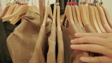 Kara Cuma indirim mağazasından kıyafet seçen bir kadının yakın çekimi. Mağazadaki kıyafet seçimleri, boyut çeşitleri, tatil indirimleri.